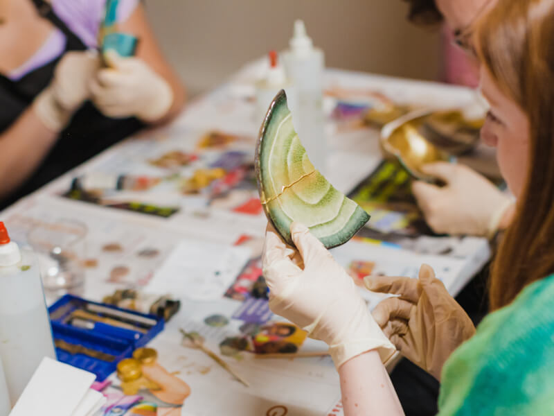 Woman wearing gloves working with pottery in a kintsugi class